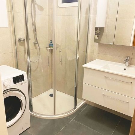 Badezimmer mit einer Waschmaschine, Duschkabine und Waschbecken